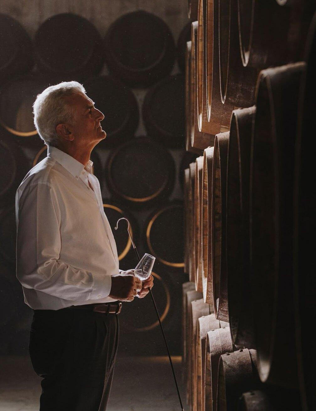 The cellar master studying a glass of brandy among the barrel racks.
