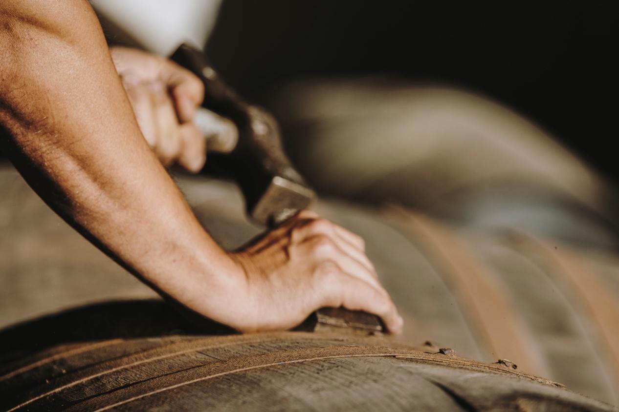 A craftsman working by hand at the head of an oak barrel.